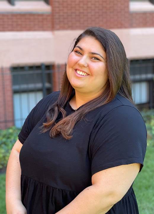 Gabby Sabat Gabby Sabat, wearing all black, smiles at the camera while standing in front of DuBourg Hall.