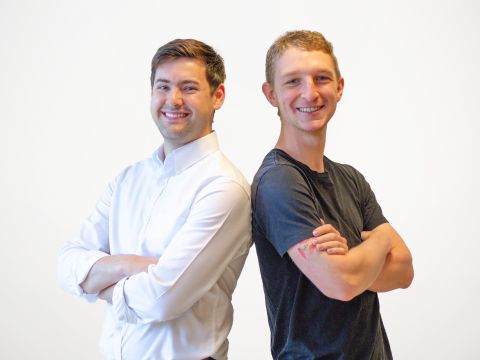 GenAssist Two men stand back to back smiling with arms folded
