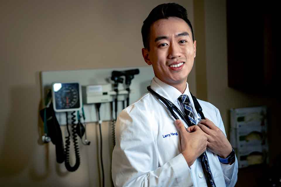 A medical student poses for a photo in a doctor's office simulation lab.