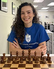 Gabriela Feller Gabriela Feller poses for a photo while sitting in front of a chess board
